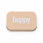 A closed, beige rectangular tin with "huppy" printed in white lowercase letters on the lid, on a white background.