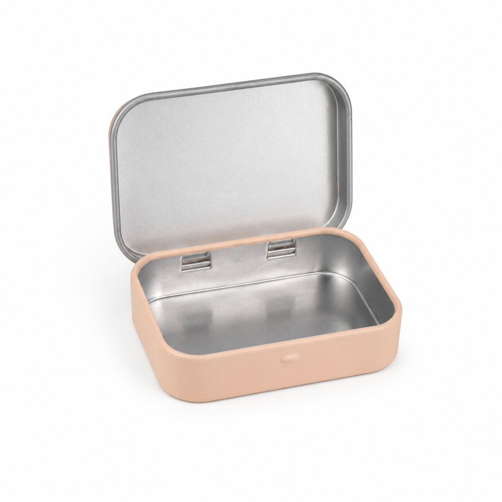 An open, empty beige tin showing its silver metallic interior, angled slightly to the side on a white background.