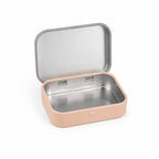 An open, empty beige tin showing its silver metallic interior, angled slightly to the side on a white background.