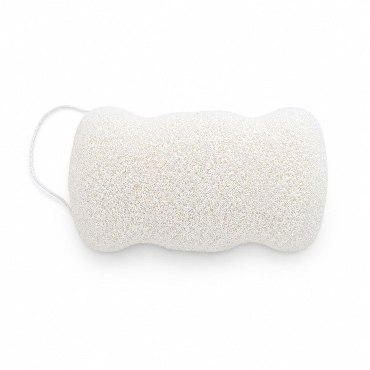 Flat, porous underside of a white konjac body sponge with an attached hanging cord, on a white surface.
