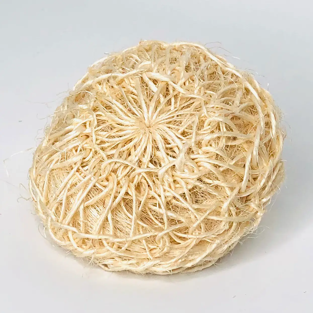 Round beige woven sisal exfoliating body sponge on a white background.