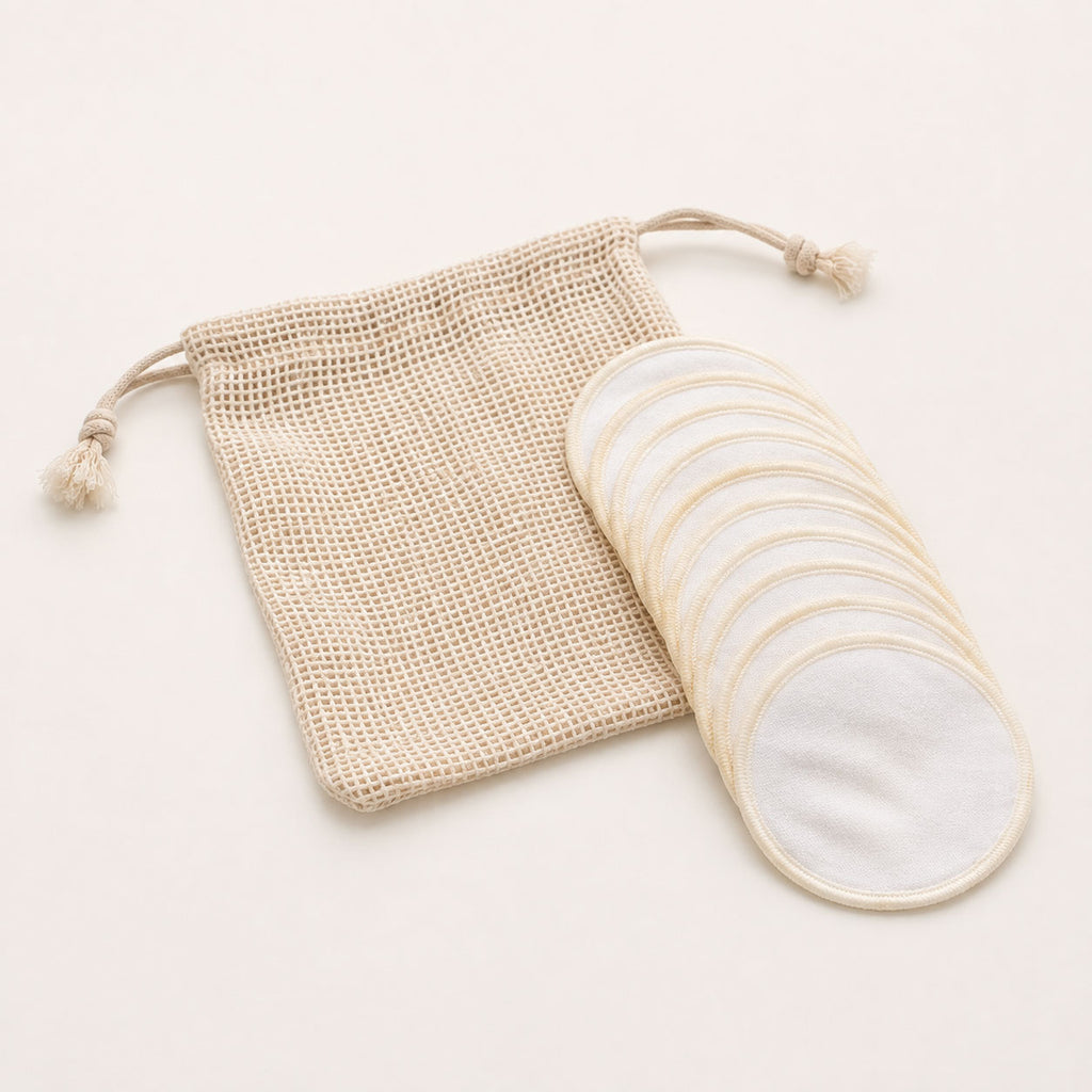 Stack of reusable white cotton pads fanned out beside a beige mesh drawstring wash bag.