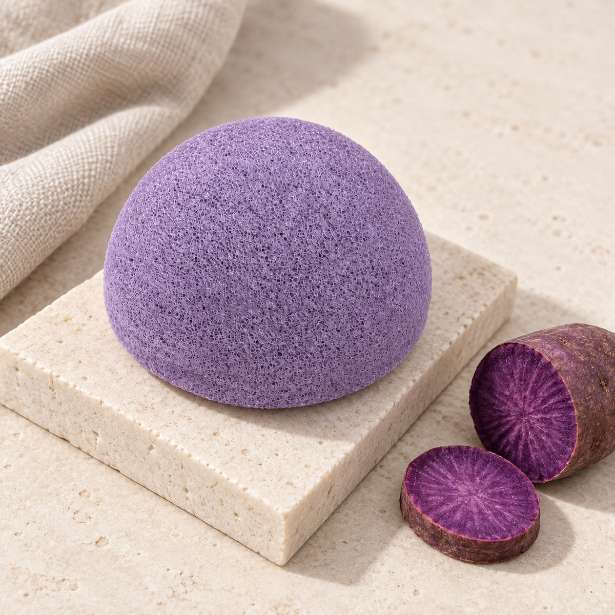 Purple dome konjac sponge resting on a stone tile beside cut slices of purple sweet potato.