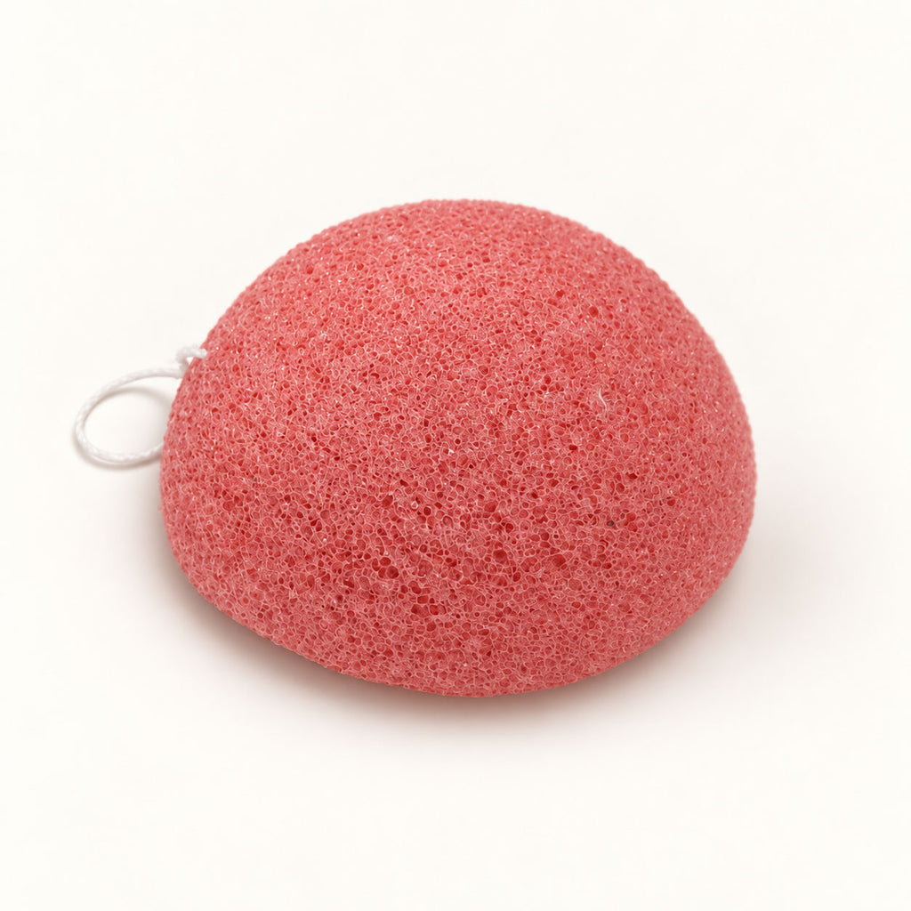 Coral-pink konjac sponge with a small white hanging string, set on a white background.