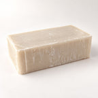 Rectangular bar of textured, off-white soap on a solid white background.