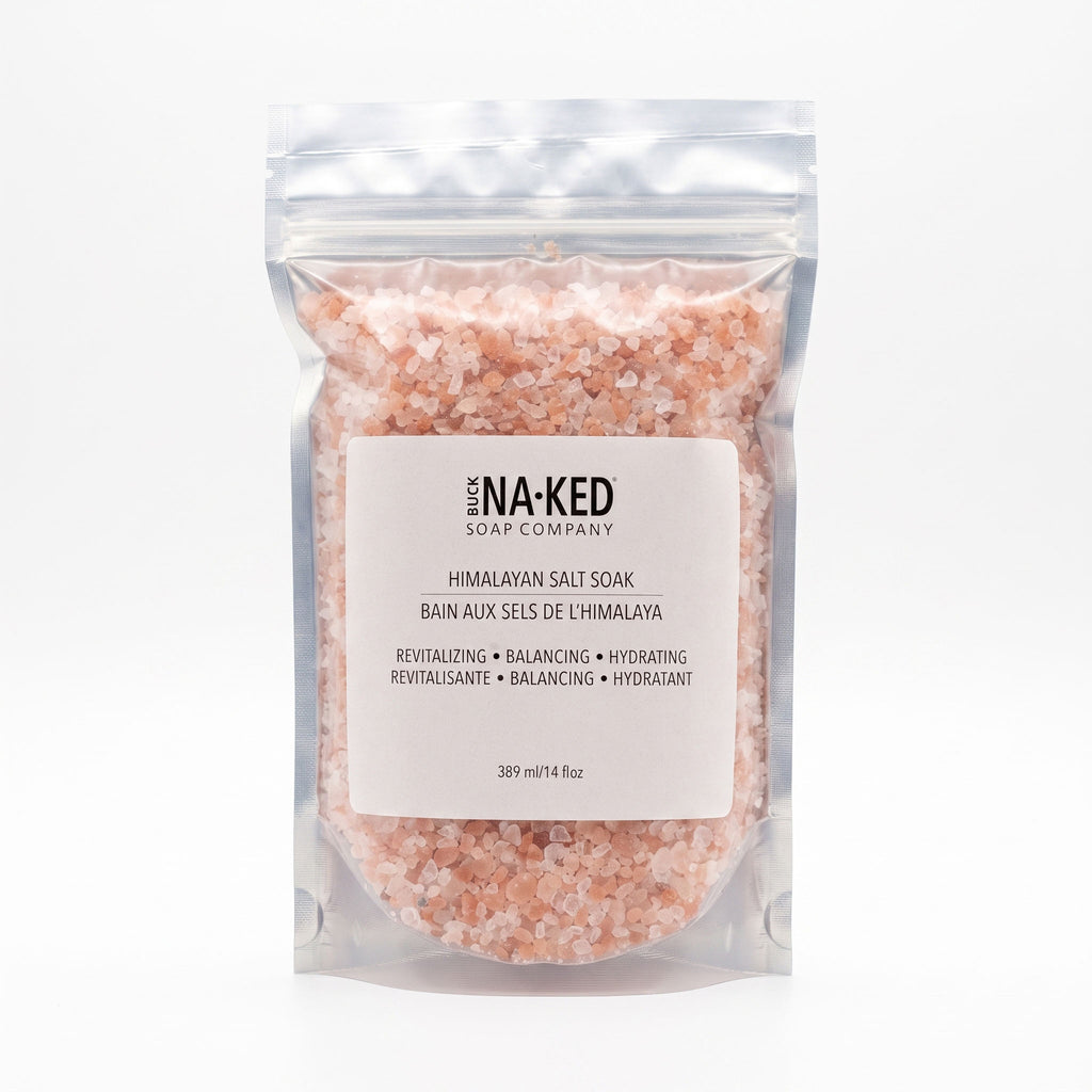A transparent pouch filled with pink Himalayan salt crystals, featuring a white Buck Naked Soap Company label.
