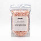 A transparent pouch filled with pink Himalayan salt crystals, featuring a white Buck Naked Soap Company label.