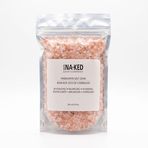 A transparent pouch filled with pink Himalayan salt crystals, featuring a white Buck Naked Soap Company label.