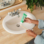 Hands applying Dr. Bronner's Spearmint organic toothpaste to bamboo toothbrush over bathroom sink demonstrating daily natural oral care routineRetry