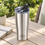 Brushed stainless steel Heritage tumbler with flip-back spout lid open on an outdoor patio table