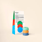 A white HiBAR sampler box next to three small, stacked solid conditioner bars in green, orange, and blue.