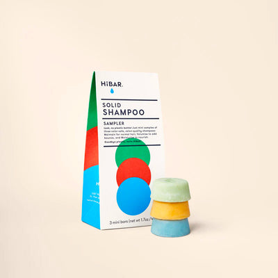 A white HiBAR Solid Shampoo Sampler carton beside three stacked round mini bars in pastel green, yellow, and blue.
