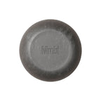 Nimbi Shave Foam Puck in charcoal next to its white paper carton showing 0.5% activated charcoal and organic shea butter ingredients