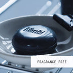 Nimbi charcoal shave puck resting on a wire-rimmed soap dish next to a black safety razor, labelled Fragrance Free
