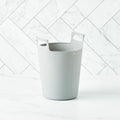 A grey Bamboozle Martha Stewart silicone liner bag for a compost bin, set on a marble surface.