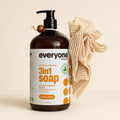 Everyone Cedar and Citrus 3-in-1 soap bottle beside a natural cream ramie bath pouf with cotton hanging cord