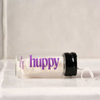 huppy dental floss jar lying on its side on white surface, showcasing the sleek glass container design and purple branding with floss visible inside