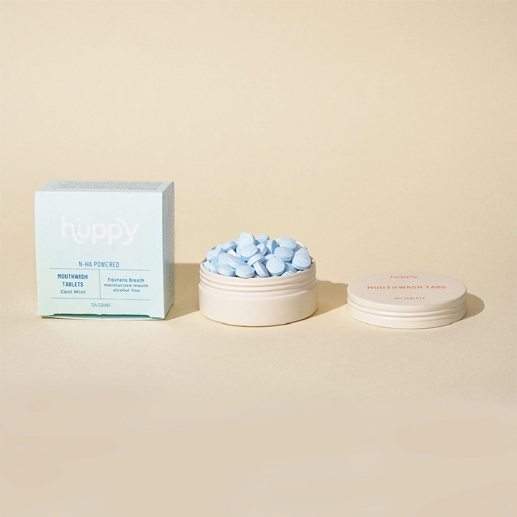A set of Huppy Cool Mint Mouthwash Tablets, with a box and several tablets displayed in front on a light background.
