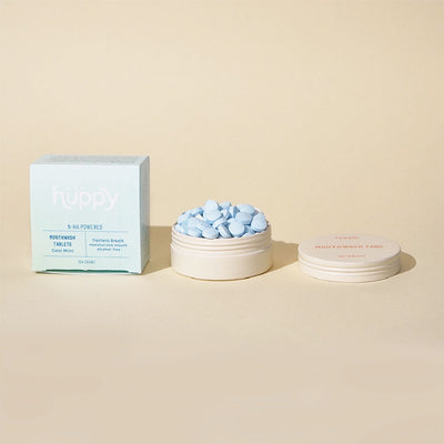 A set of Huppy Cool Mint Mouthwash Tablets, with a box and several tablets displayed in front on a light background.