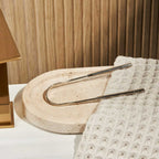 huppy tongue cleaner lifestyle shot - stainless steel scraper positioned on modern stone bathroom tray with textured towel, demonstrating elegant bathroom integration and daily use context