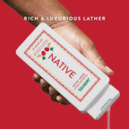 A hand pours clear gel from a Native Jarritos Passion Fruit body wash bottle against a solid red background.