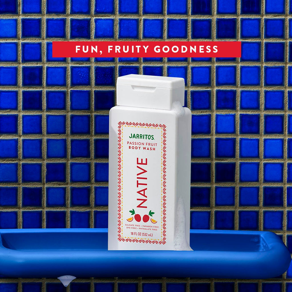Native Jarritos Passion Fruit body wash bottle covered in suds on a blue tray against blue mosaic shower tiles.