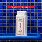 Native Jarritos Passion Fruit body wash bottle covered in suds on a blue tray against blue mosaic shower tiles.