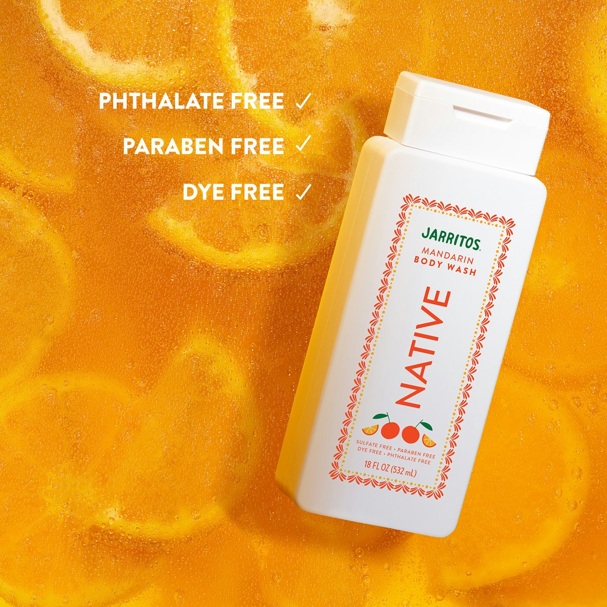 Native Mandarin body wash bottle lying in bubbly orange liquid filled with submerged citrus slices.