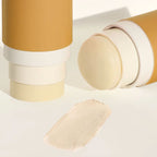 Routine Bonita Applebom deodorant with its cap removed, revealing the pale-yellow stick beside a swatch of its creamy texture on a beige-toned surface.
