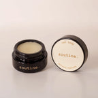 Routine Cat Lady botanic perfume balm - open black glass jar showing cream-coloured solid perfume with detached lid displaying product name - natural moisturizing fragrance balm