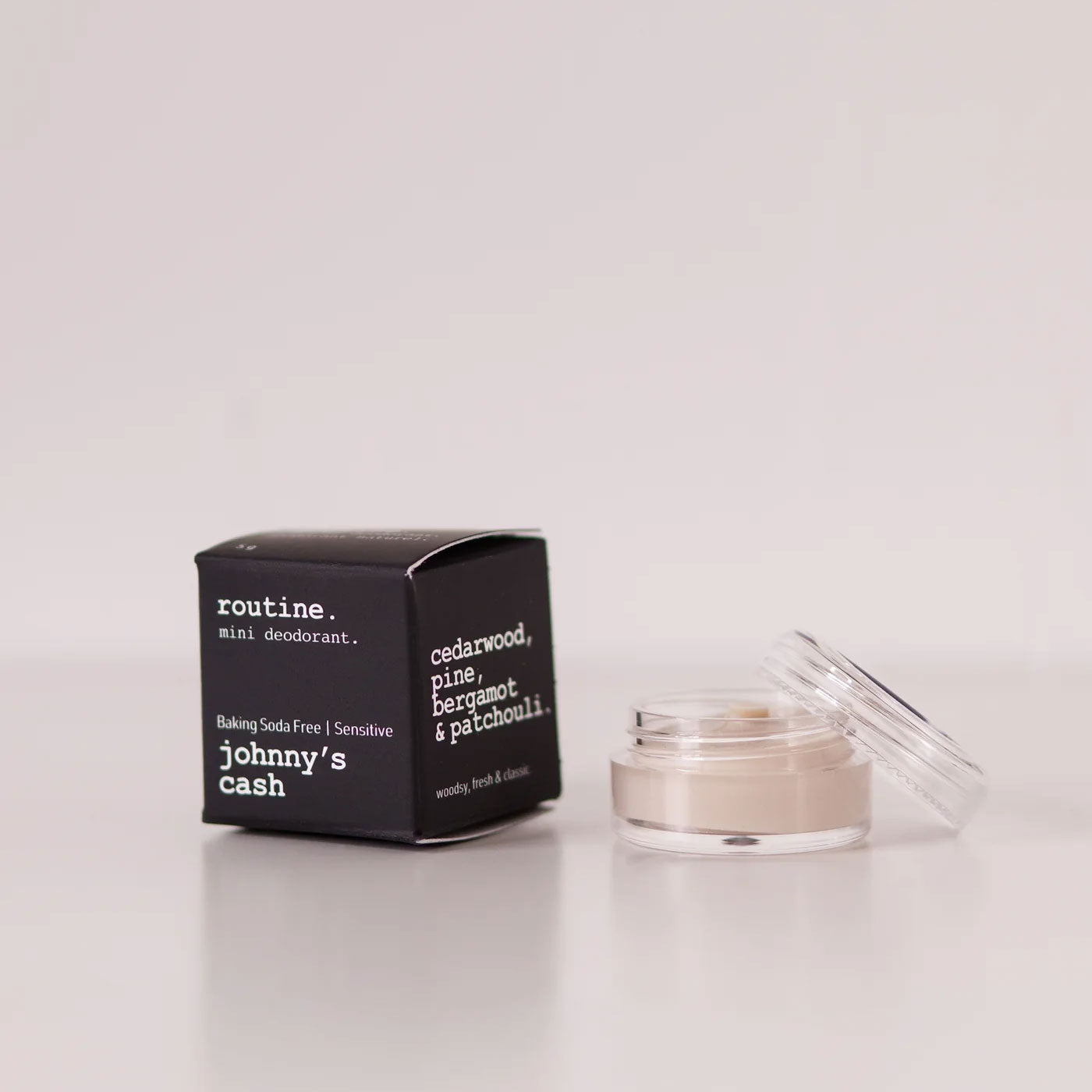 Routine Johnny's Cash baking soda free mini deodorant showing black cardboard packaging next to open glass jar containing cream-coloured natural forest-scented deodorant