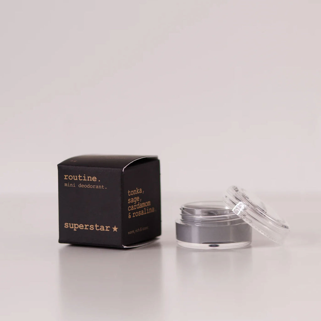 Routine Superstar mini deodorant showing black packaging with gold text next to open glass jar containing charcoal-grey natural deodorant with activated charcoal