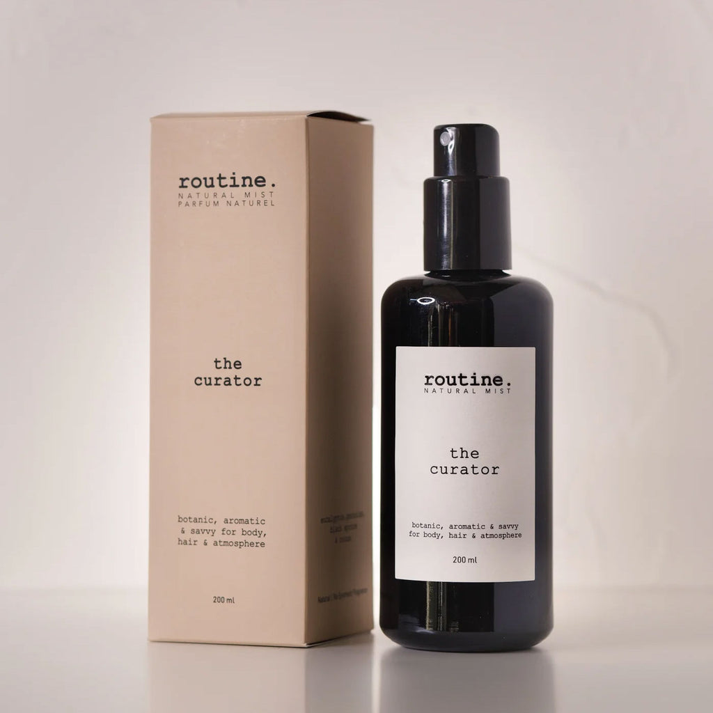 Routine The Curator natural mist bottle - black glass spray bottle with beige cardboard packaging showing botanical aromatic savvy description - eucalyptus geranium cocoa essential oil formula for body hair and atmosphere