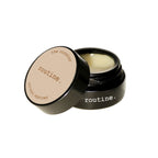 Routine The Curator solid perfume - black glass jar with cream label open revealing golden balm texture