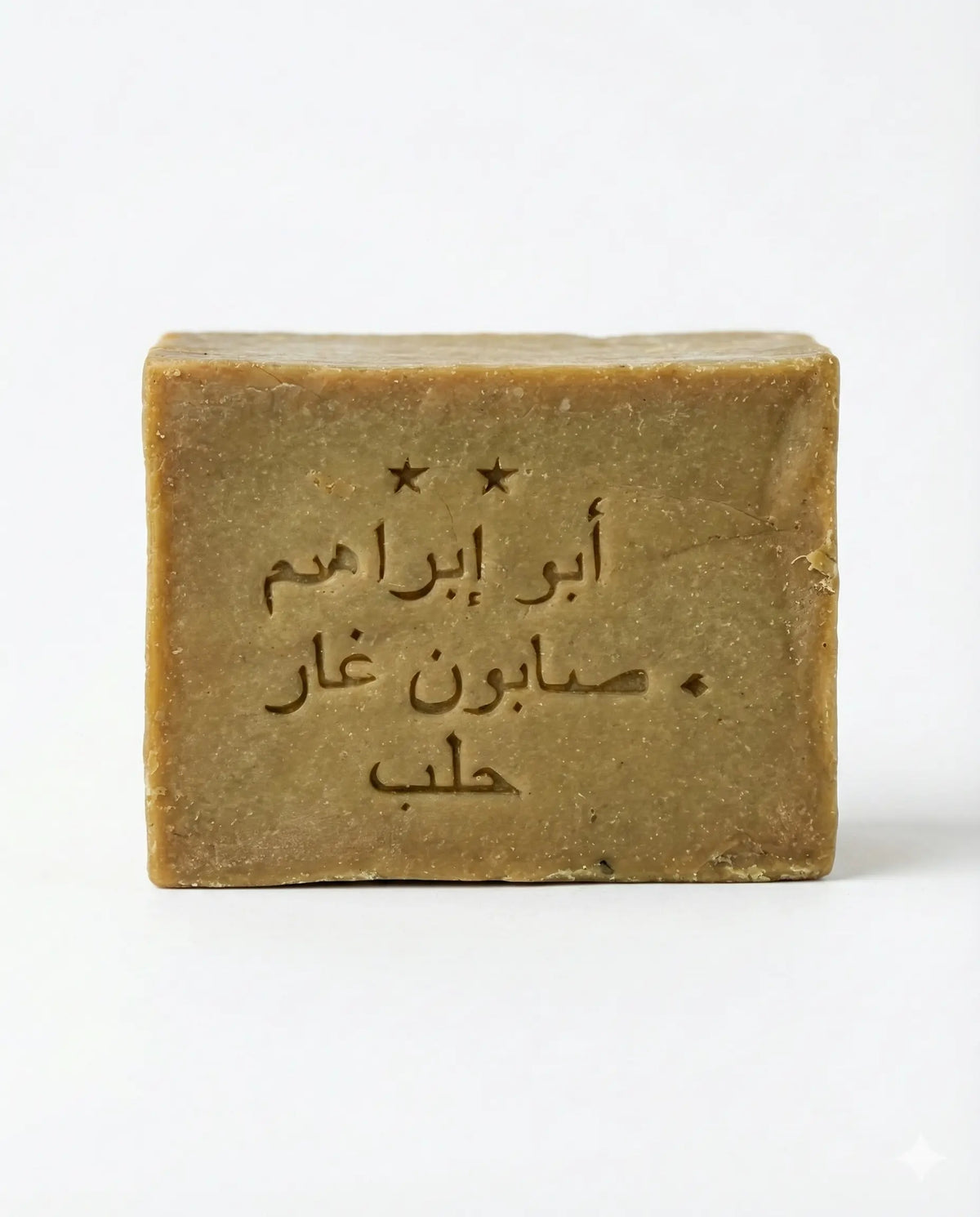 Front view of an olive-tan Aleppo soap bar stamped with Arabic text and two stars on a plain white background.