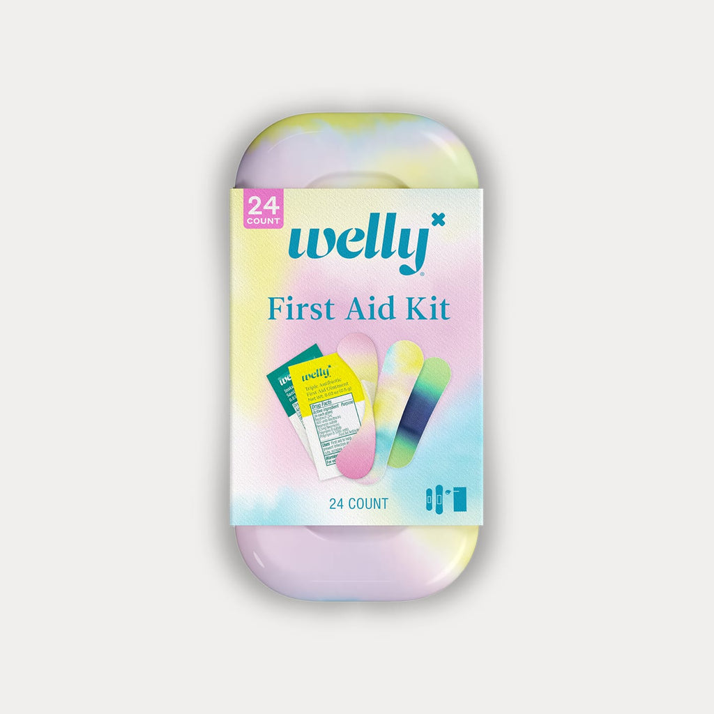 A tie-dye patterned Welly First Aid Kit tin wrapped in a pastel-coloured paper label on a grey background.