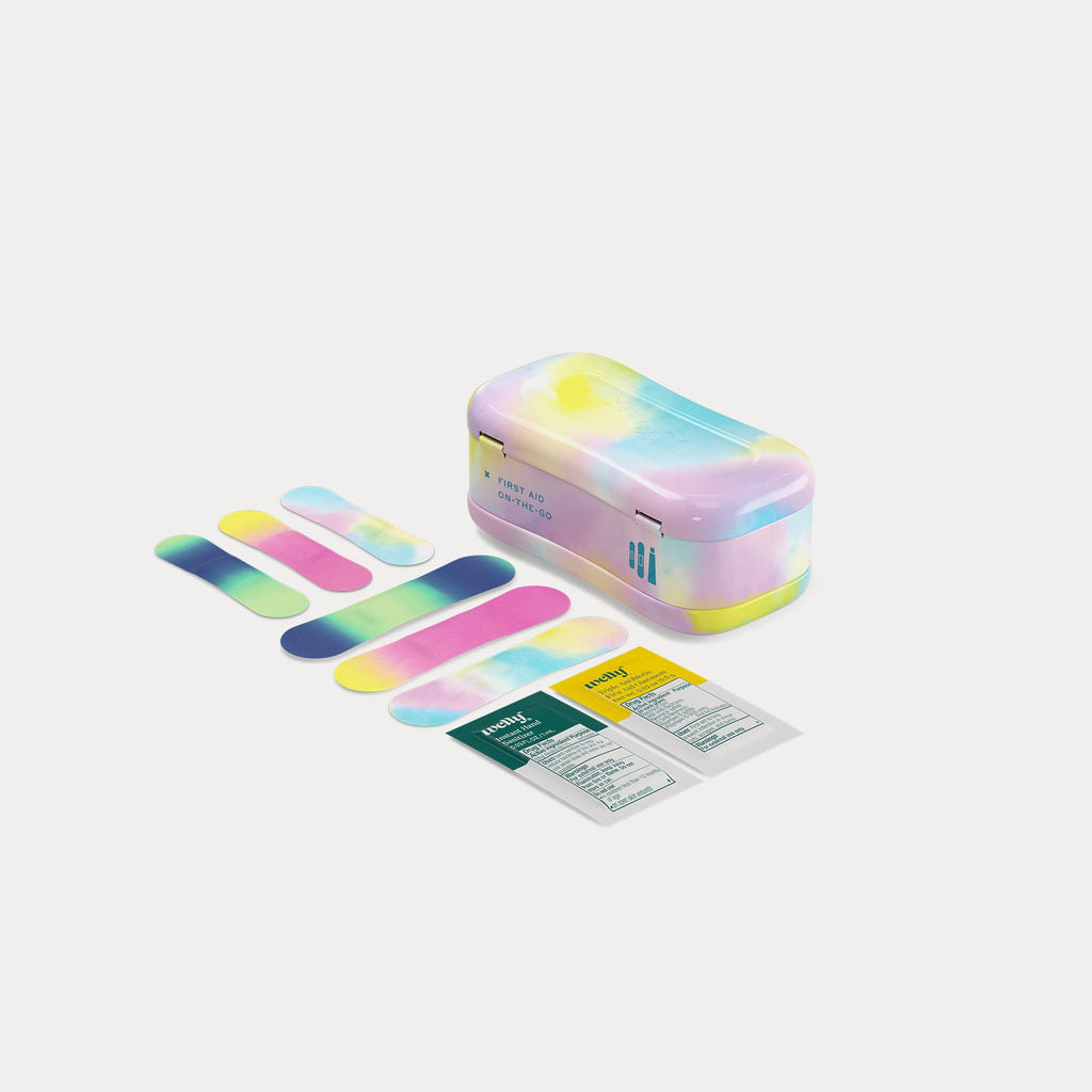 A closed tie-dye tin next to six colourful patterned bandages and two first aid ointment packets.