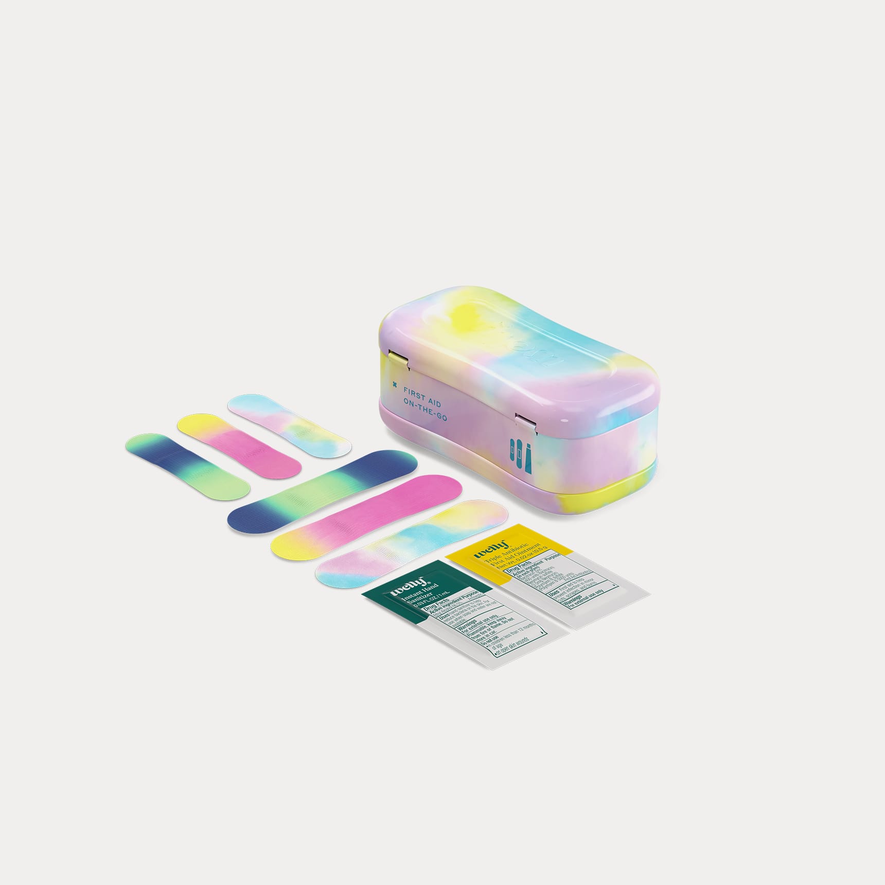 A closed tie-dye tin next to six colourful patterned bandages and two first aid ointment packets.