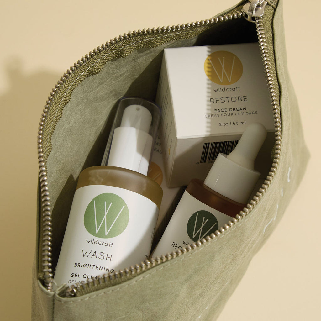 An open olive green Wildcraft pouch filled with skincare products, including a gel cleanser, face cream, and serum.