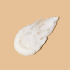 A thick textured smear of white cream conditioner on a solid beige background.