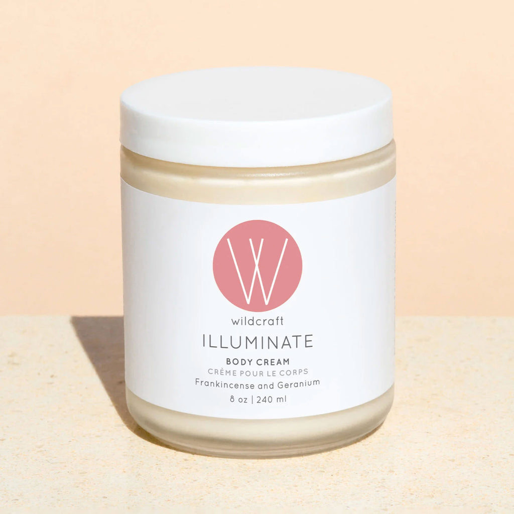 A jar of Wildcraft Illuminate Body Cream with a white label, featuring the product name and the scent, Frankincense and Geranium.