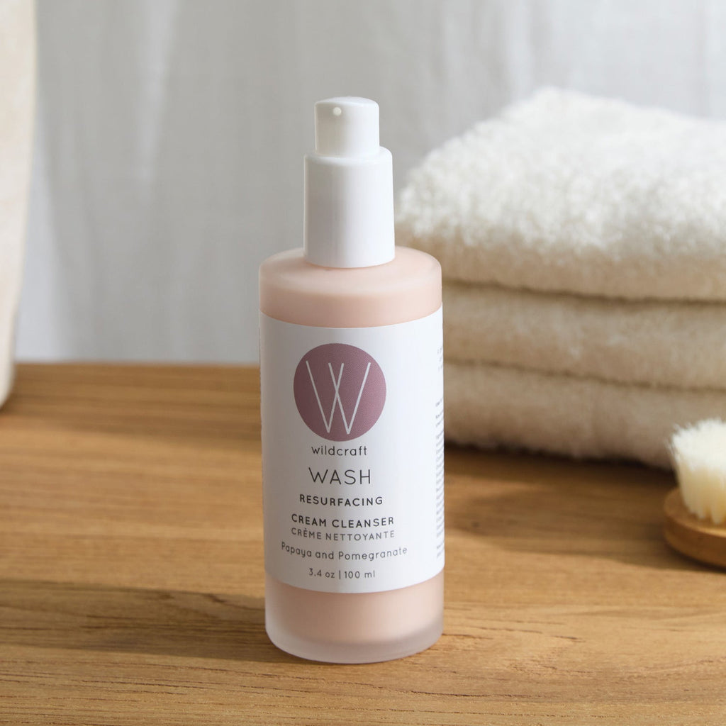 Wildcraft cleanser bottle with cap removed on a wooden countertop, with a soft white towel in the background.