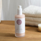 Wildcraft cleanser bottle with cap removed on a wooden countertop, with a soft white towel in the background.