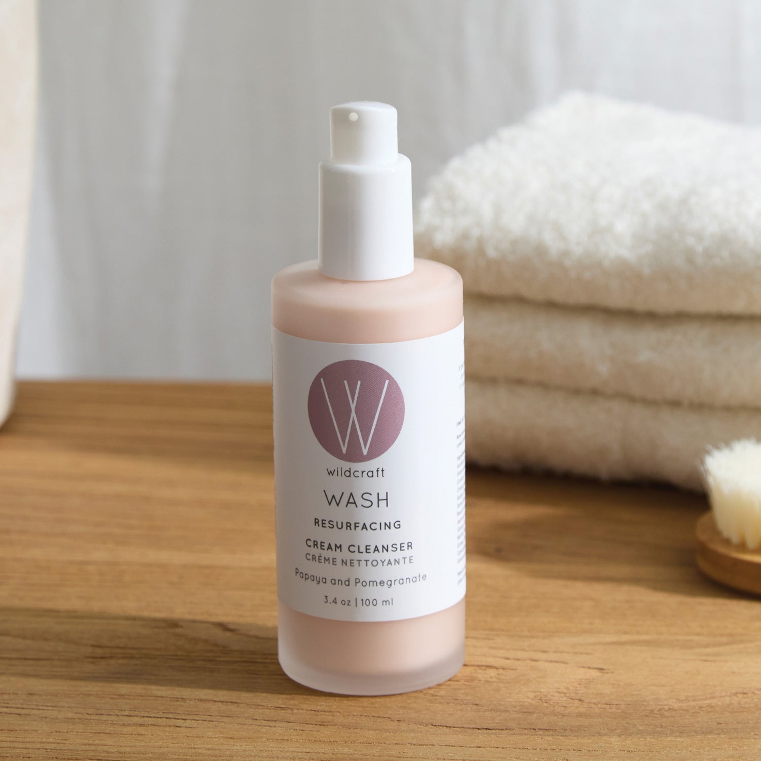 Wildcraft cleanser bottle with cap removed on a wooden countertop, with a soft white towel in the background.