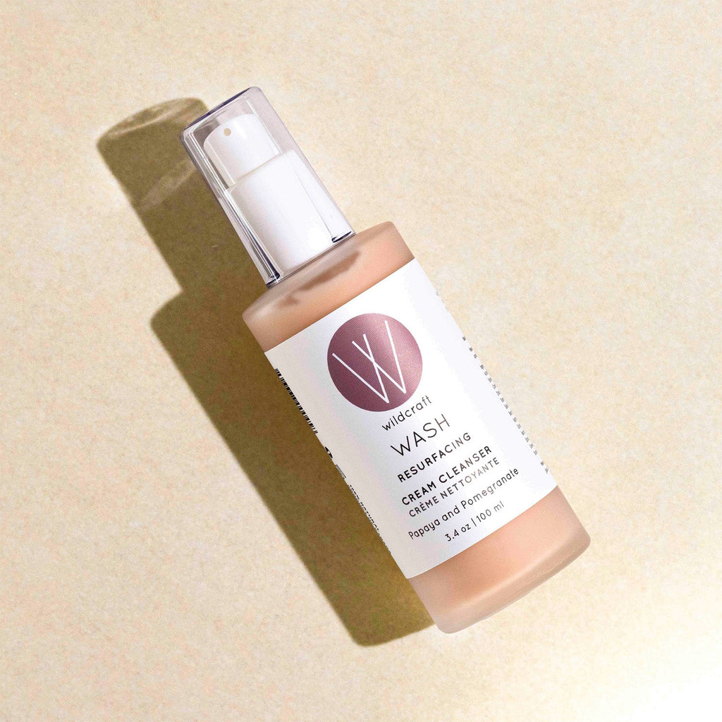 A Wildcraft Wash Cream Cleanser bottle lying diagonally on a textured beige surface with a sharp shadow.