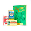 A collection of Duke Cannon brand soaps arranged in front of a green package with 'Frothy The Beer Man' written on it. The soaps are labeled with different names and have packaging resembling beer cans and labels.