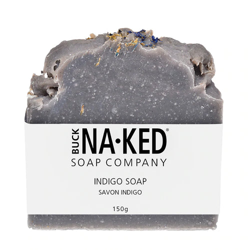 A bar of grey-blue indigo soap wrapped in a white Buck Naked Soap Company paper label, against a white background.