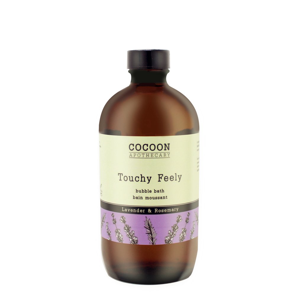 A glass bottle of Cocoon Apothecary Touchy Feely bubble bath with lavender and rosemary, with a label that includes the product name and aromatherapy benefits.